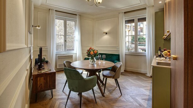 A dining area with a round table, two chairs, a vase with flowers, and a chandelier. - Art Apartment Luxury Ponte Vecchio Suite (Firenze)