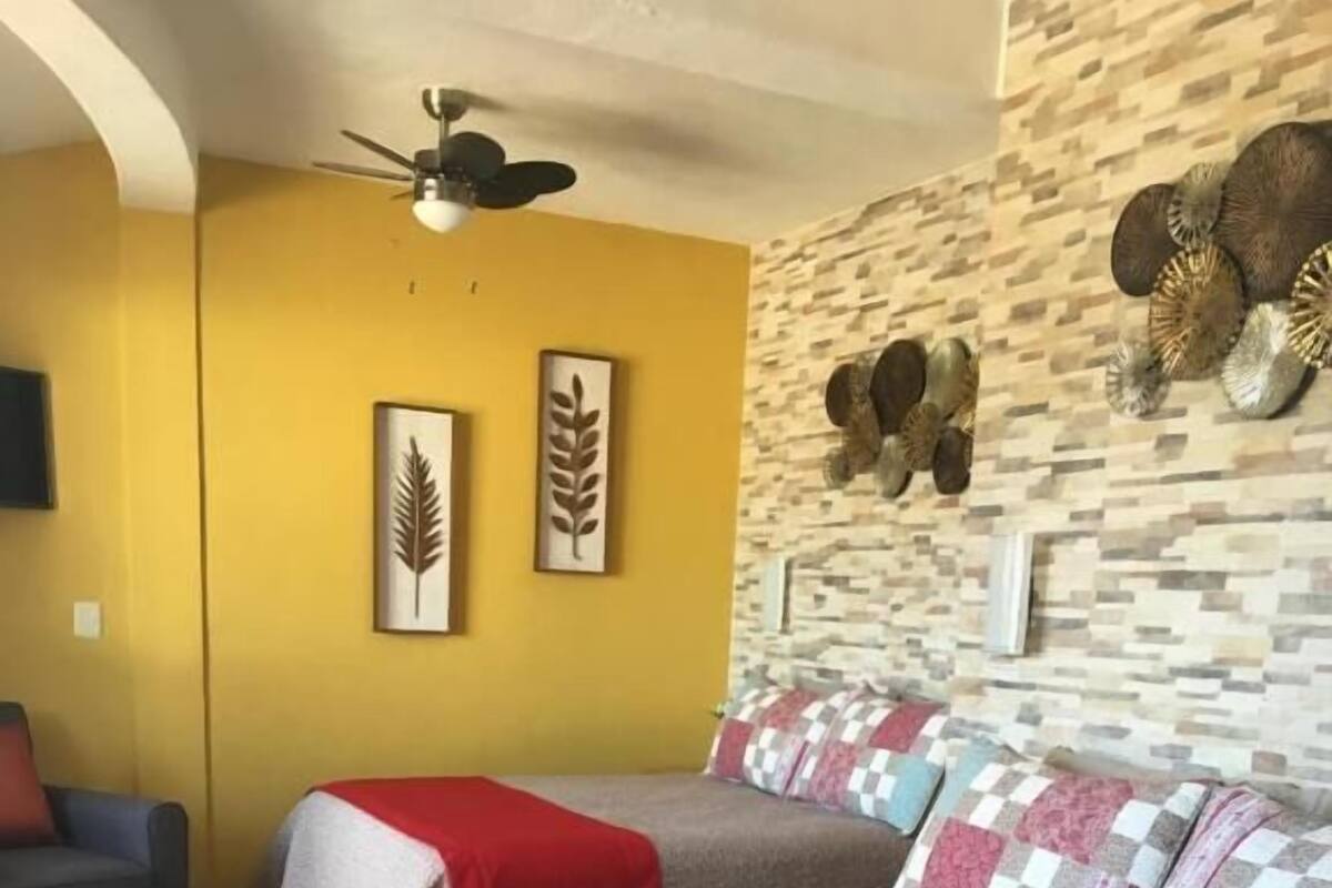 Habitación de hotel con dos camas, una pared de piedra y un ventilador de techo.