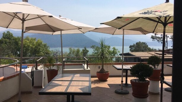 An outdoor terrace with tables and chairs, umbrellas, and potted plants. - Casa Cielo (Valle de Bravo)