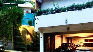 A two-story building with a garage containing two cars. - Casa Cielo (Valle de Bravo)