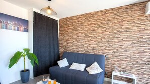 A modern living room with a dark blue sofa, a potted plant, a coffee table with drinks, and a wall with a wooden plank pattern. - Casa Dolce Vita (Borgo)