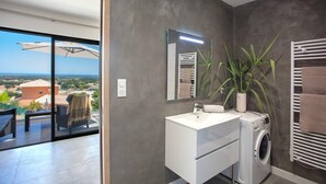 A modern bathroom with a large mirror, a white sink, a washing machine, and a potted plant. - Casa Dolce Vita (Borgo)