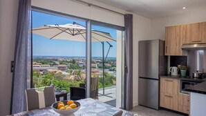 A modern kitchen with a view of a cityscape, a dining area with a table and chairs, and a large sliding glass door. - Casa Dolce Vita (Borgo)