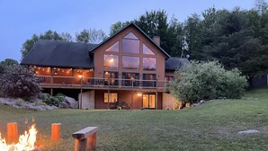 A large wooden cabin with a balcony, a fire pit, and a well-maintained lawn. - Cozy Log Cabin - Nature Escape - 5 acres (Iola)