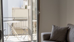 A balcony with a table and chairs, a grey sofa, and a sliding glass door. - Acropolis Urban Life (Athens)