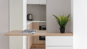A modern kitchen with a wooden countertop, a potted fern, and a kettle in the background. - Acropolis Urban Life (Athens)