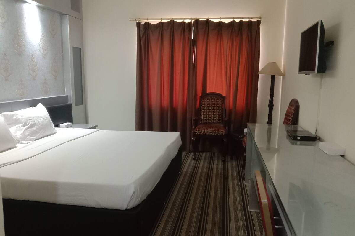 Une chambre d’hôtel avec un lit, une chaise, une télévision et un bureau.