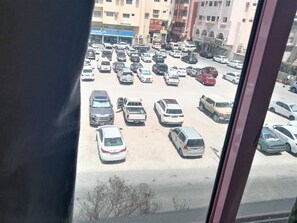 A parking lot with various vehicles, including cars and vans, and buildings in the background. - Al Commodore Hotel (Manama)