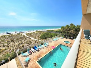 Un espace piscine avec des chaises longues et vue sur la plage.