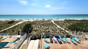 Vista de una playa con zona de piscina, tumbonas y cielo despejado.