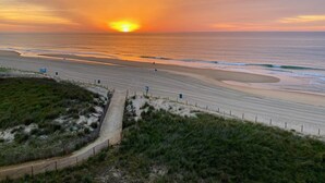 Een strand met een houten looppad dat naar het strand leidt, zand en de oceaan.
