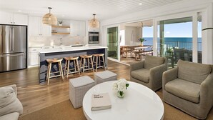 Een moderne keuken met een centraal eiland, barstoelen en een eethoek met uitzicht op de oceaan.