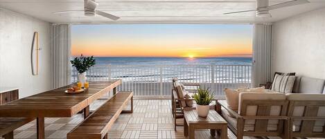 A spacious balcony with a wooden floor, a dining table with benches, and a sofa.