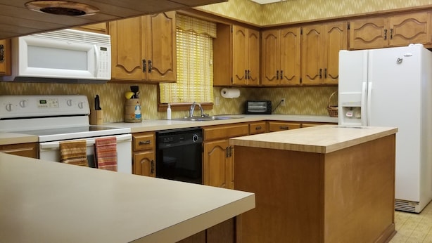 A kitchen with wooden cabinets, a microwave, a stove, a dishwasher, and a refrigerator.