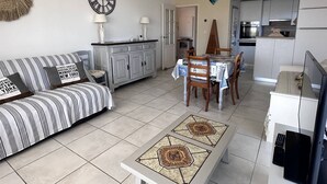 Una sala de estar con sofá, mesa de comedor y zona de cocina.