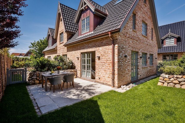 A brick house with a patio, a dining table, and chairs.
