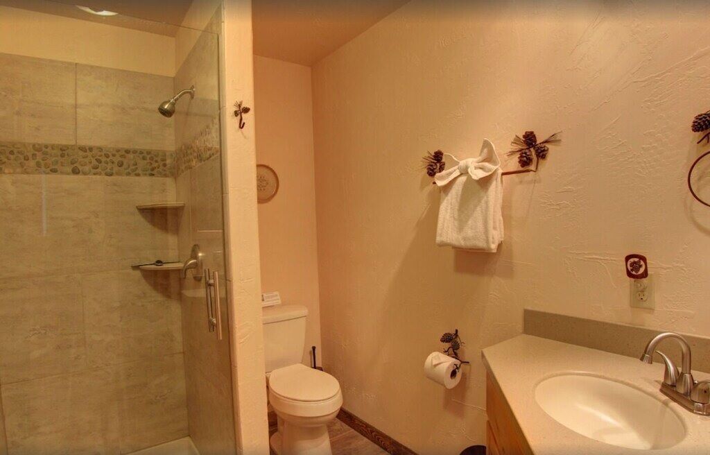 A bathroom with a glass-enclosed shower, a toilet, a sink, and decorative wall elements.