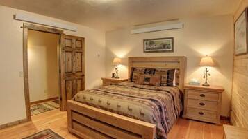 A bedroom with a wooden bed, two bedside tables with lamps, a wooden wardrobe, and a rug on the floor.