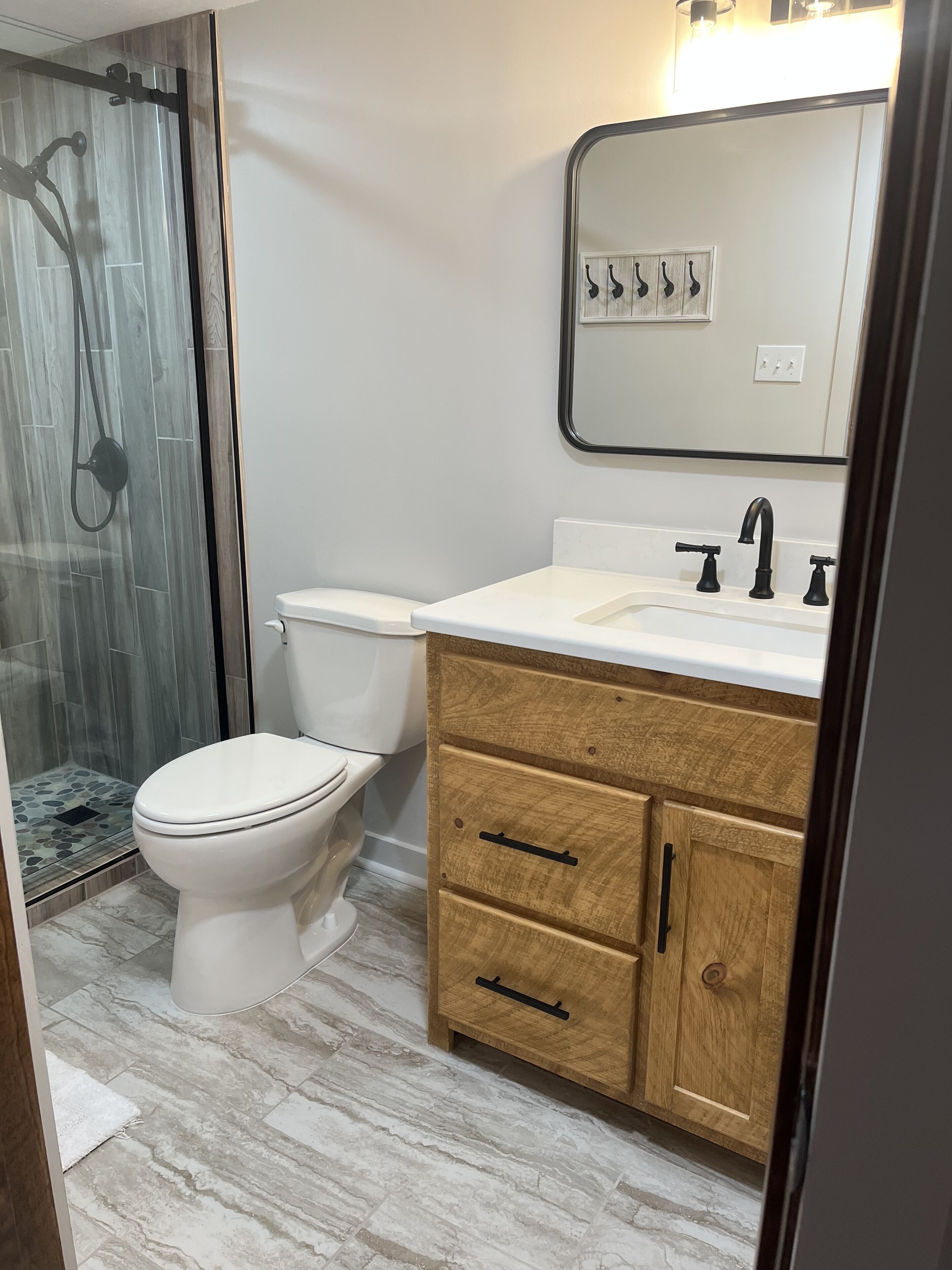 Une salle de bain comprenant des toilettes, un espace douche, un lavabo avec un miroir et des meubles en bois.