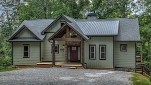 Une cabane rustique avec des fondations en pierre, un porche à l’avant et une cheminée.