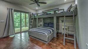 Une chambre avec un lit superposé, une échelle, un ventilateur de plafond et une fenêtre avec des rideaux.