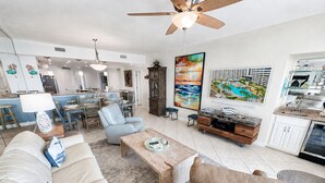 A spacious living area with a sofa, coffee table, and a dining area with chairs and a table. - Eden W 903 A remodeled beautiful 1 Bedroom 2 Bath Gulf Front Condo with Stunning Views! (Pensacola)