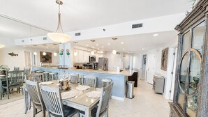 A spacious kitchen with a central island, dining area with chairs, and a large decorative mirror. - Eden W 903 A remodeled beautiful 1 Bedroom 2 Bath Gulf Front Condo with Stunning Views! (Pensacola)