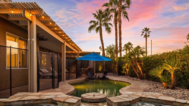 Ein Poolbereich mit Whirlpool, Liegestühlen und einer Pergola mit Lichterketten.