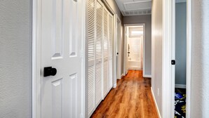 A hallway with white doors, a wooden floor, and a light-colored wall.