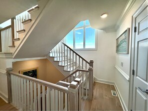 Staircase leads to an upper level with a window and framed artwork.