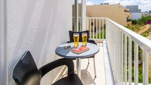 En balkon med et bord, to stole og to ølglas.