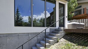 Een modern huis met grote ramen, een betonnen trap en een houten terras.
