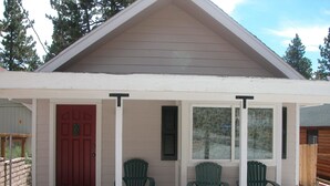 A covered porch with a red door, two green chairs, and a window with patterned glass. - Super clean 2 bedroom/2 bath Walk to Sledding & Tubing located in Big Bear Lake (Big Bear Lake)