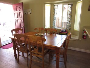 A dining room with a wooden table and chairs, a door, and a window with curtains. - Super clean 2 bedroom/2 bath Walk to Sledding & Tubing located in Big Bear Lake (Big Bear Lake)