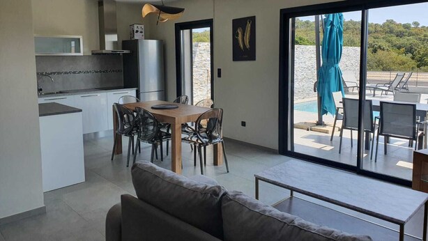 A modern kitchen with a dining area, a sofa, and a view of the outdoors. - Porto Vecchio villa with private heated pool near Saint Cyprien beach (Porto-Vecchio)