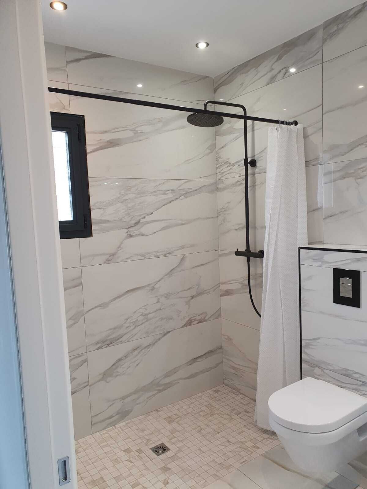 A modern bathroom with a walk-in shower, a toilet, and a mirror.
