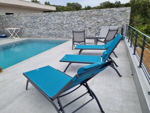 Un espace piscine comprenant trois chaises longues et une table.