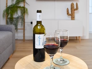 Una bottiglia di vino e due bicchieri su un tavolo rotondo in legno in un soggiorno.
