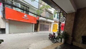 Vista de la calle con un escaparate rojo con la leyenda 'AMI HOMES' y una motocicleta estacionada al lado.