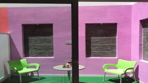 A room with two green chairs, a small round table, and a purple wall with two windows. - Orange 1: Studio Apartment in St. Julian's (Swieqi)