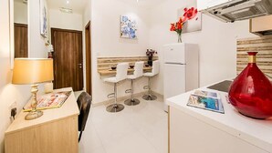 A modern kitchen with white cabinets, a central island, and three bar stools. - Orange 1: Studio Apartment in St. Julian's (Swieqi)