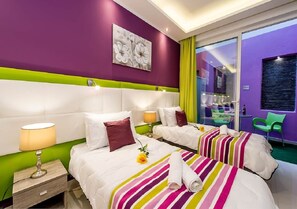 Une chambre d’hôtel avec deux lits, un mur d’accent vert, une grande fenêtre et une vue sur l’extérieur.