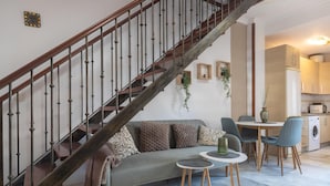 A modern living area with a staircase, sofa, dining table, chairs, and a kitchen in the background. - ATICO CASTILLO - Fantastic apartment with sea views and free WiFi. (Fuengirola)