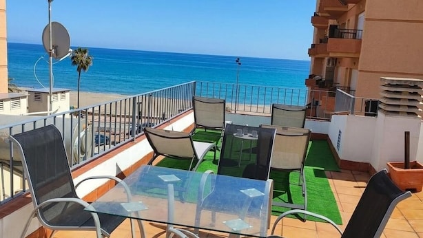 A balcony with a glass table and chairs, overlooking a beach and the sea. - ATICO CASTILLO - Fantastic apartment with sea views and free WiFi. (Fuengirola)