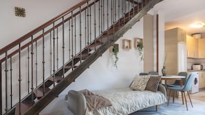 A modern living room with a wooden staircase, a sofa, a dining table, and a kitchen area. - ATICO CASTILLO - Fantastic apartment with sea views and free WiFi. (Fuengirola)