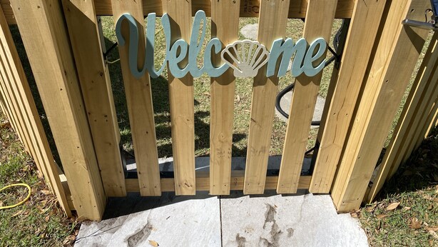 Een houten hek met een 'Welcome' bord.