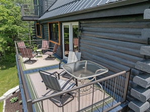 En træhytte med terrasse, udendørs møbler og et glasbord.