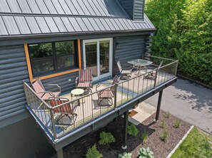 A log cabin with a balcony, outdoor seating, and a door leading to a covered patio.