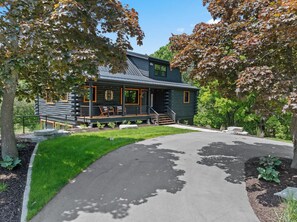 A log cabin with a porch, a staircase, and a driveway leading to the entrance. - Newly Updated Log Home on 5 acres - The Great Escape (Sister Bay)