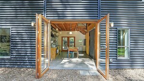Un edificio moderno con un'ampia porta aperta che dà su un'area pranzo con tavolo e sedie.